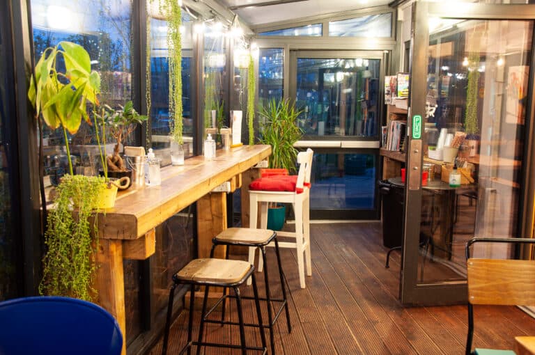 The bright glazed terrace seating with windows onto the greenery.